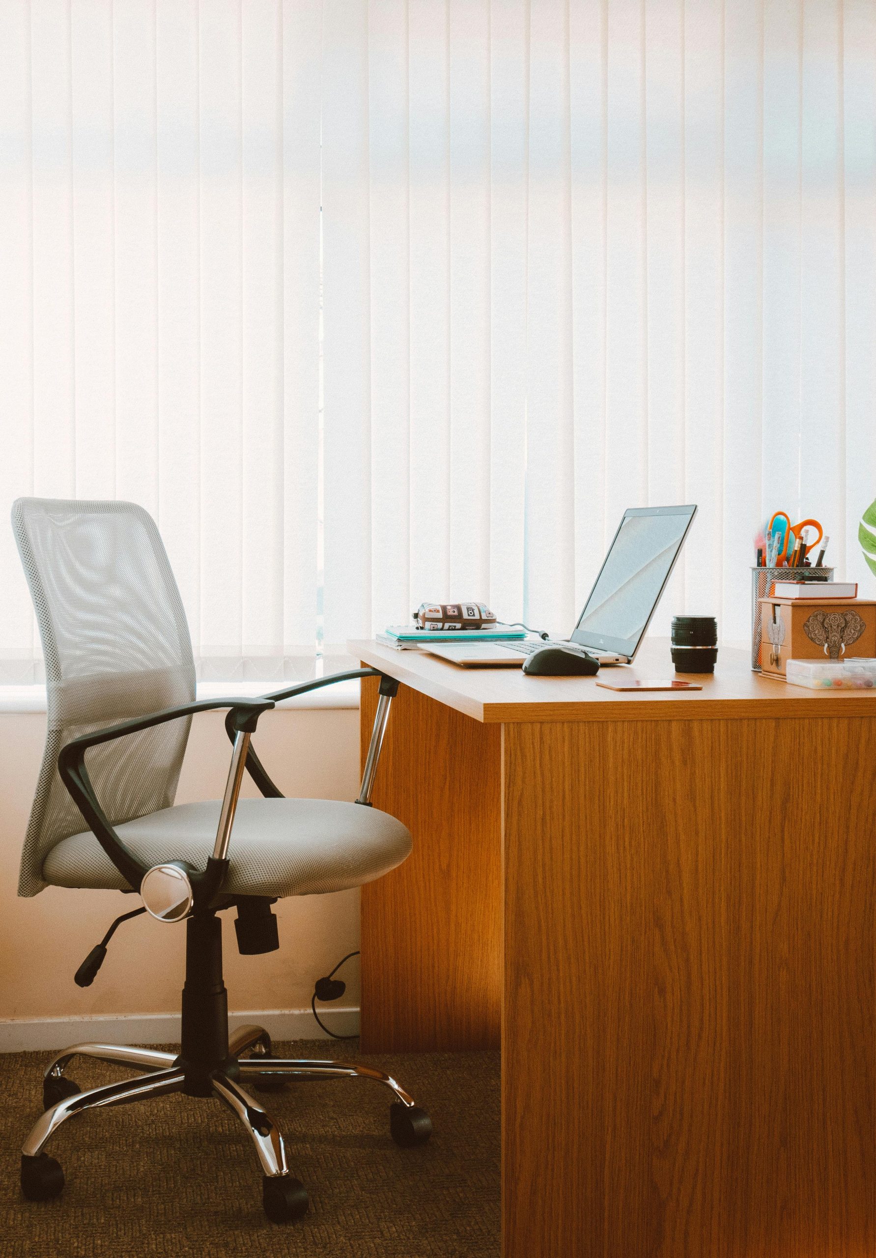 Home office with wooden desk, ergonomic chair, laptop, and natural light, showcasing remote work and modern home buyer preferences